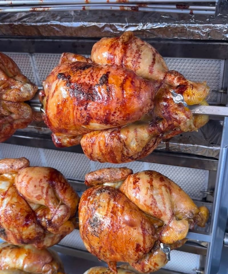 Gros plan sur des poulets fermiers dorés qui tournent sur la broche de la rôtissoire Ô Poulailler